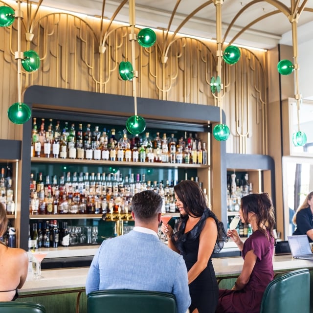 A couple drinking cocktails at the bar