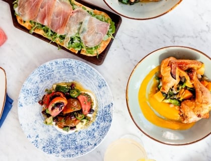 A table set with several plates of food, displaying a diverse selection of appetizing dishes for a communal dining experience.