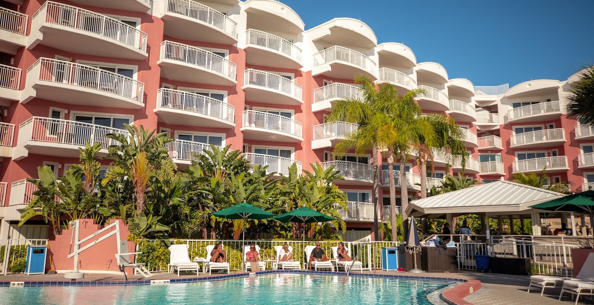 people sitting on lounge chairs by the pool