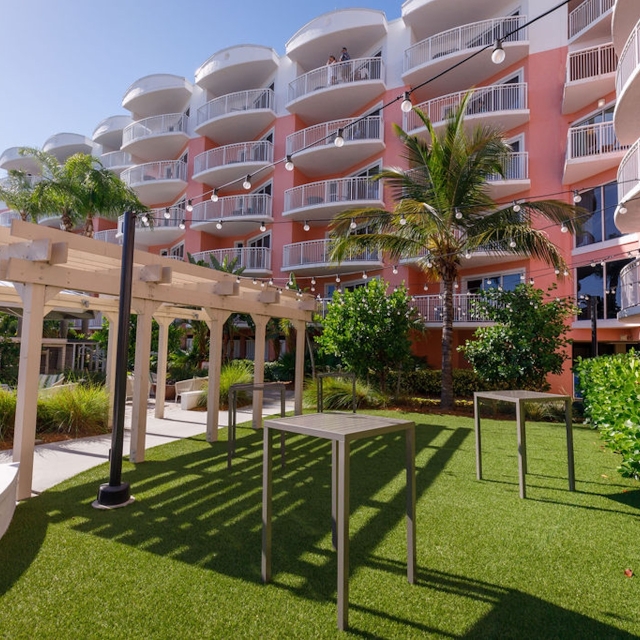 small hotel entrance with trimmed lawn and tall tables