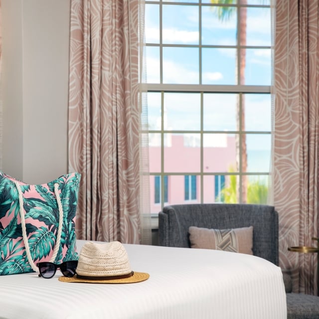 bedroom with a beach bag and sun hat laying on the bed