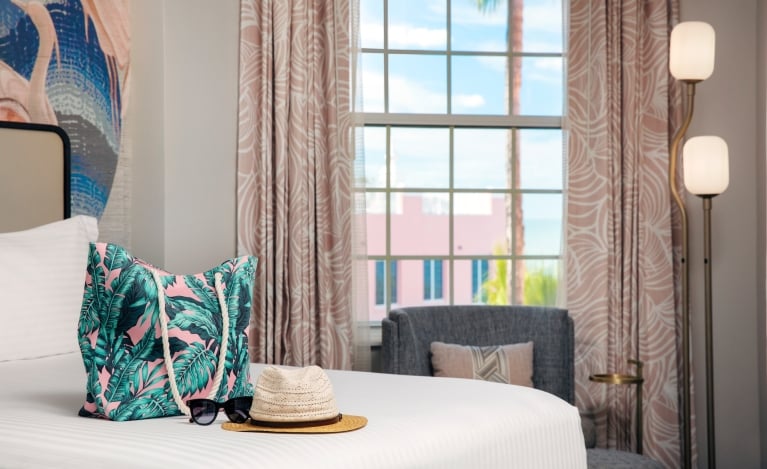 bedroom with a beach bag and sun hat laying on the bed