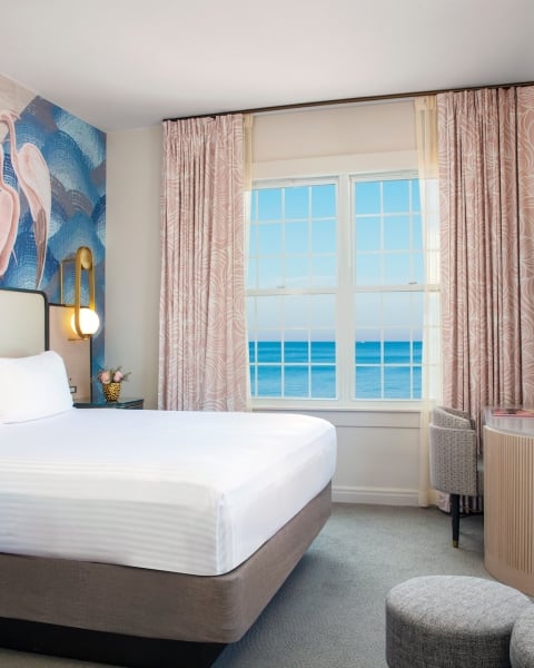 a bedroom with large windows with a view of the ocean