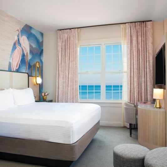 a bedroom with large windows with a view of the ocean