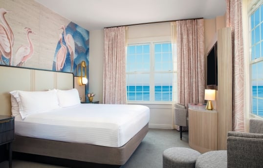 a bedroom with large windows with a view of the ocean