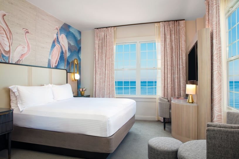 a bedroom with large windows with a view of the ocean