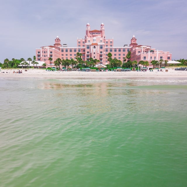 the ocean in front of a large pink hotel