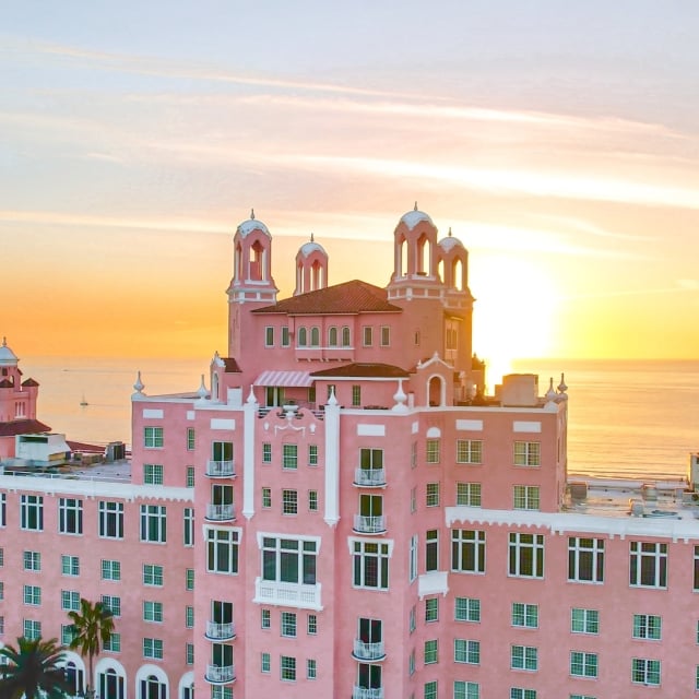 large pink hotel with the ocean in the background at sunset