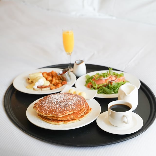 a tray of breakfast foods sitting on a bed