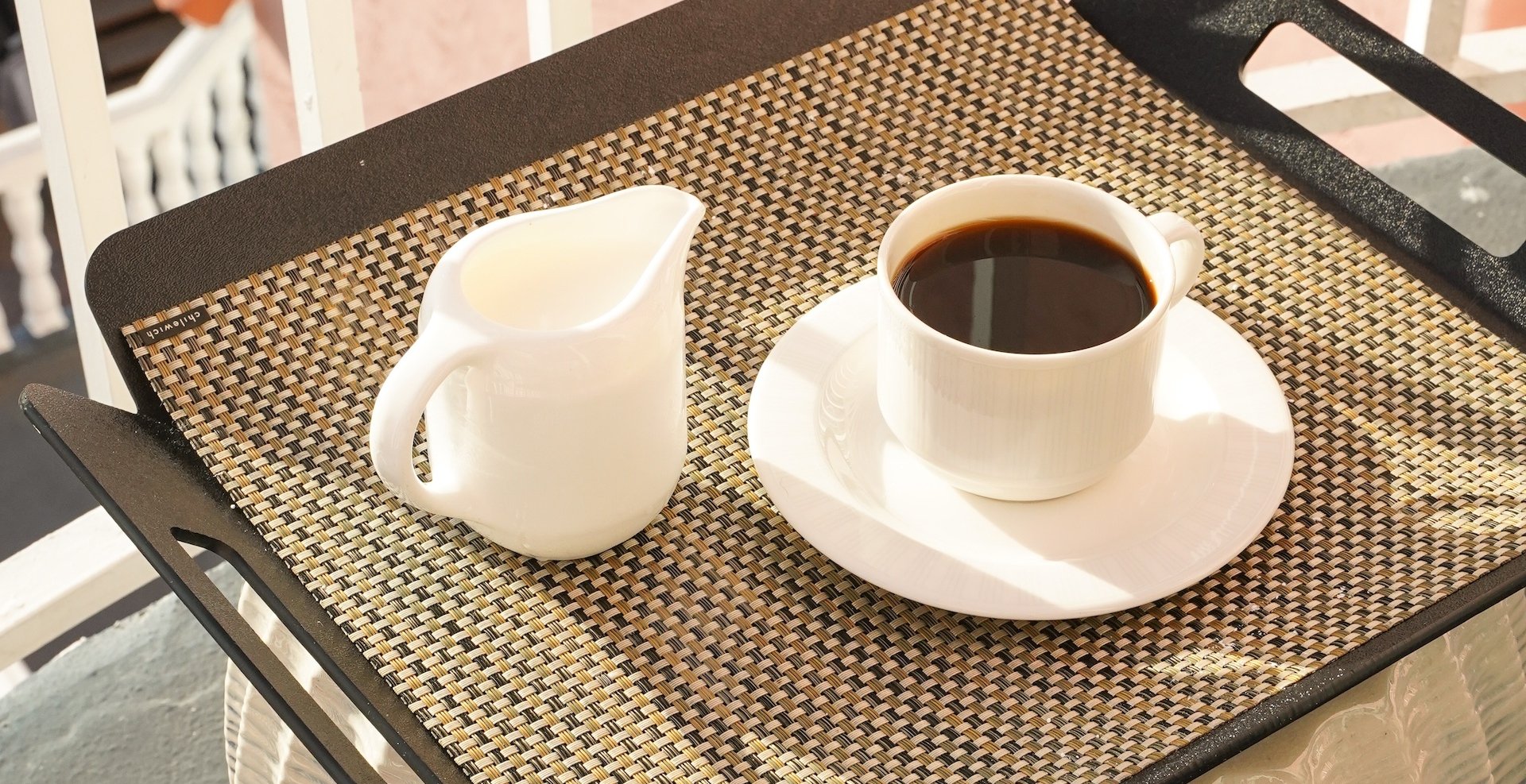 a cup of coffee and a carafe of milk on a tray