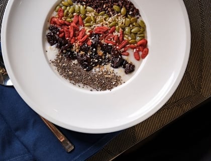 A bowl of soup topped with nuts and seeds