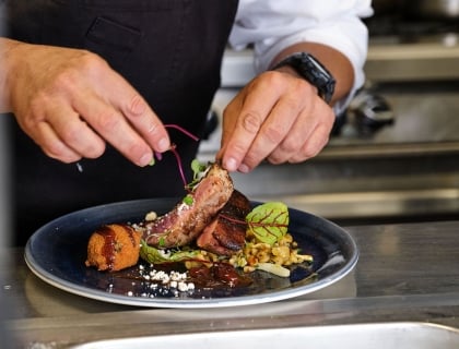 A chef skillfully arranges food on a plate, showcasing culinary artistry and attention to detail.