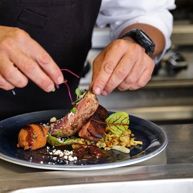 a chef adding garnish to a meal