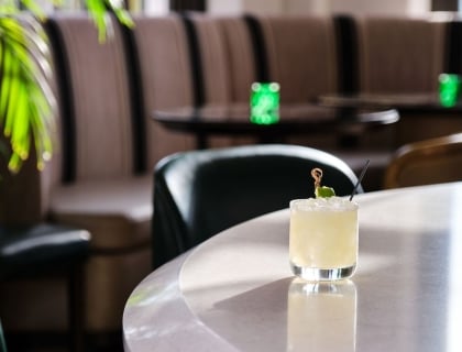 A refreshing cocktail sits on a table in a cozy restaurant, inviting guests to enjoy a delightful drink.