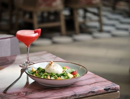 A bowl of fresh salad next to a refreshing drink.