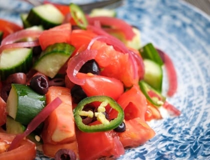 A plate of tomato cucumber salad, ready to be enjoyed.