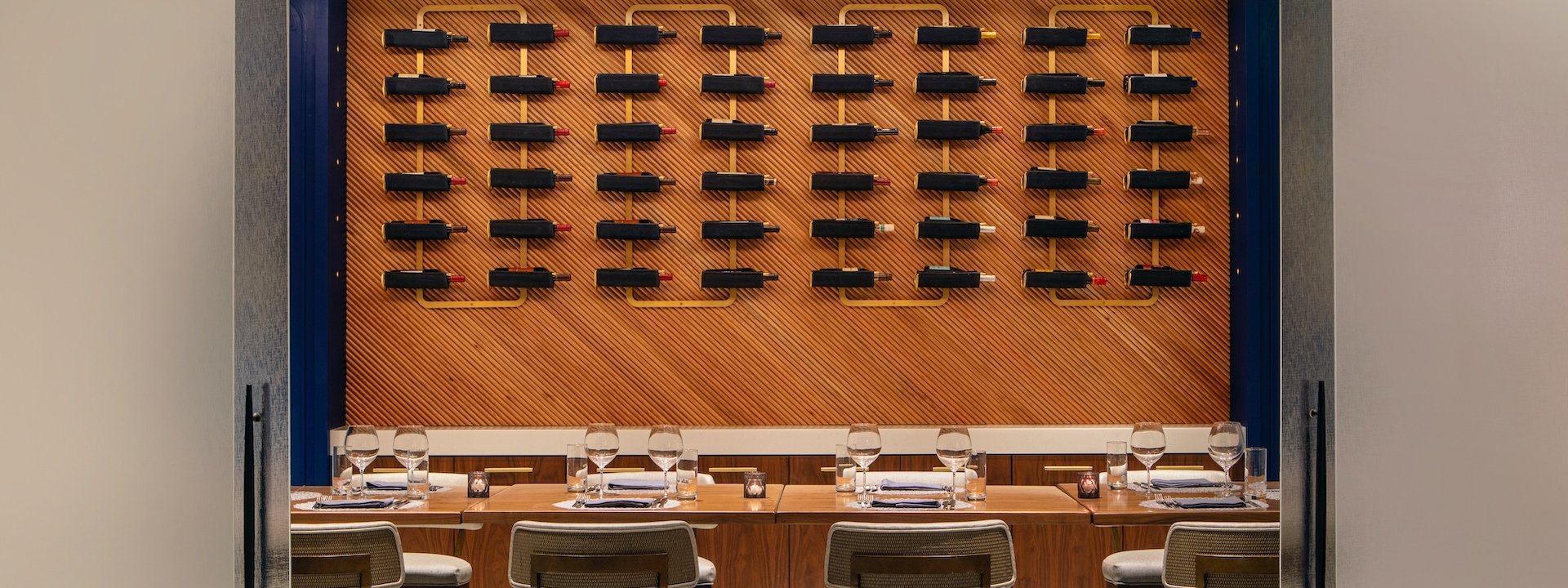 a private dining area with various bottles of wine on the wall