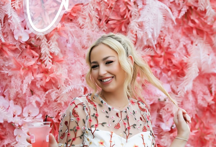 a bride drinking a cocktail in front of a pink floral backdrop