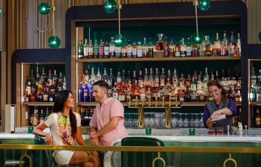 a couple sitting at the lobby bar while a bartender pours drinks