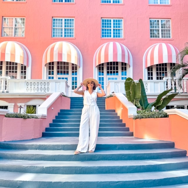 a woman in white holding her hat on a staircase