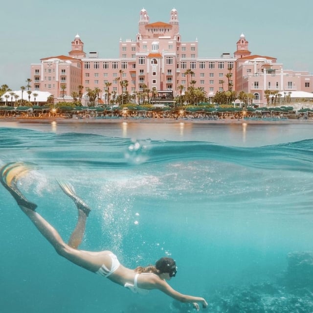 a woman diving in the water in front of The Don CeSar