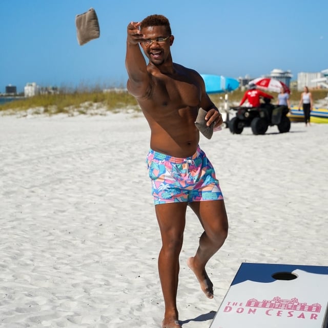 a man playing cornhole on the beach