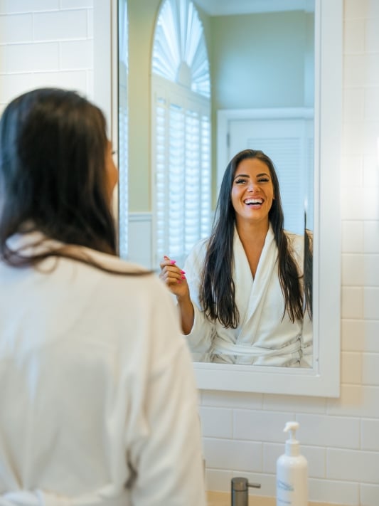 a woman in a robe smiling in a mirror