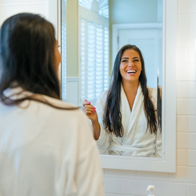 a woman in a robe smiling in a mirror