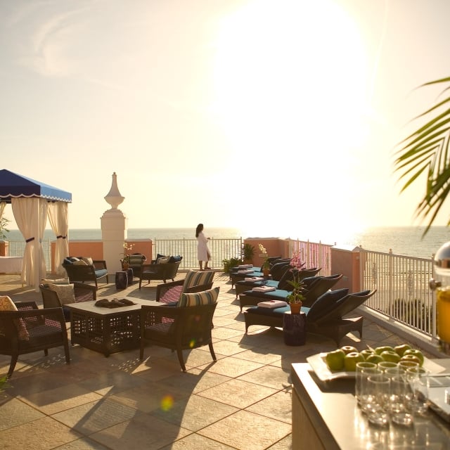 a woman in a robe looking out at the ocean on the spa balcony