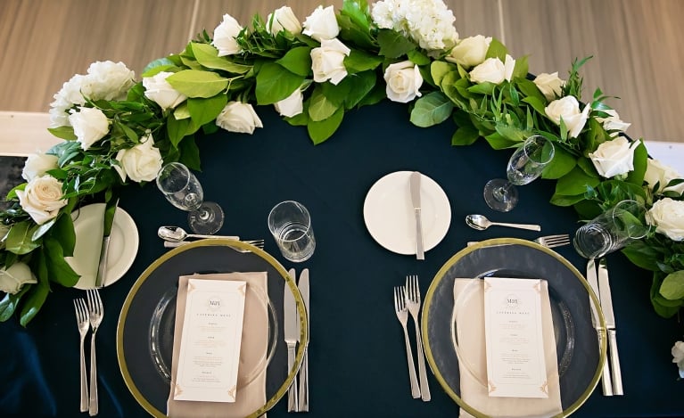 place setting with white roses and a blue table cloth