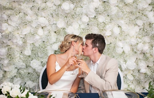 a bride and groom kissing while drinking champagne