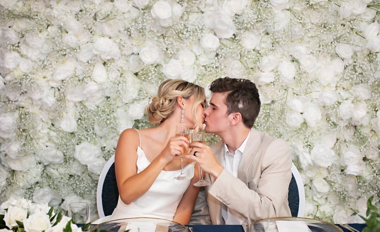 a bride and groom kissing while drinking champagne