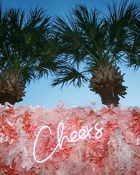 pink floral backdrop with palm trees and a neon 