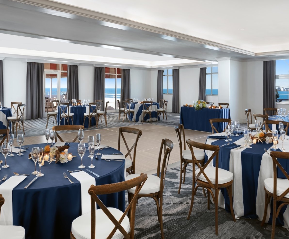 large meeting room with round tables and a view of the ocean