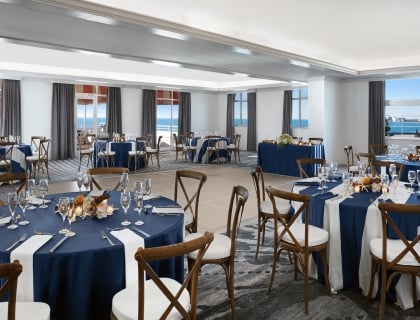 large meeting room with round tables and a view of the ocean