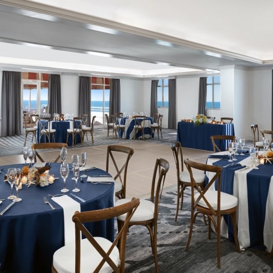 large meeting room with round tables and a view of the ocean