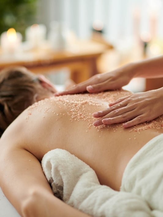 Woman getting exfoliating scrub massage in spa salon