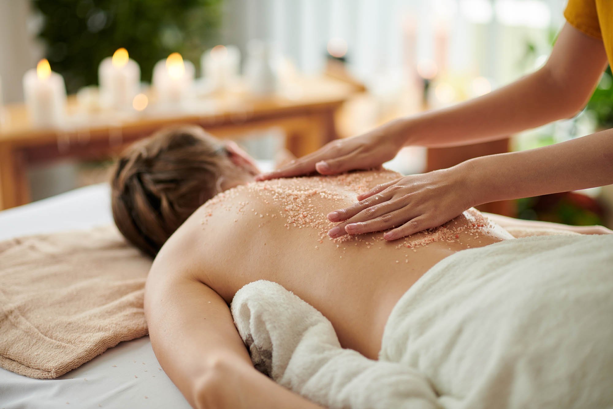 Woman getting exfoliating scrub massage in spa salon