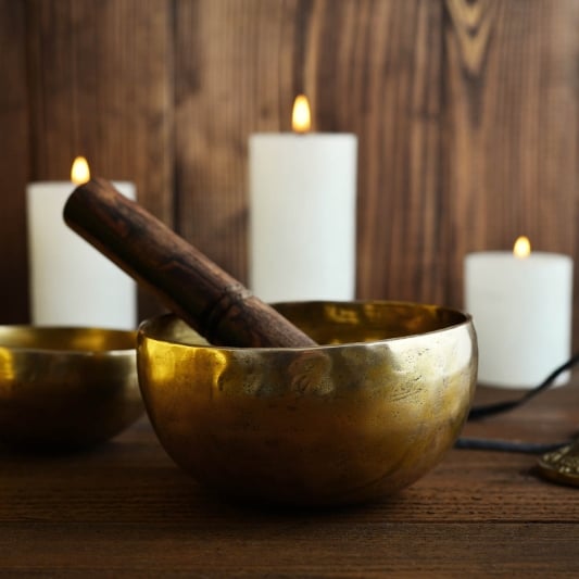 Tibetan handcrafted singing bowls with sticks on wooden background