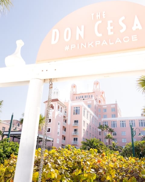 a beach swing with a large pink hotel in the background