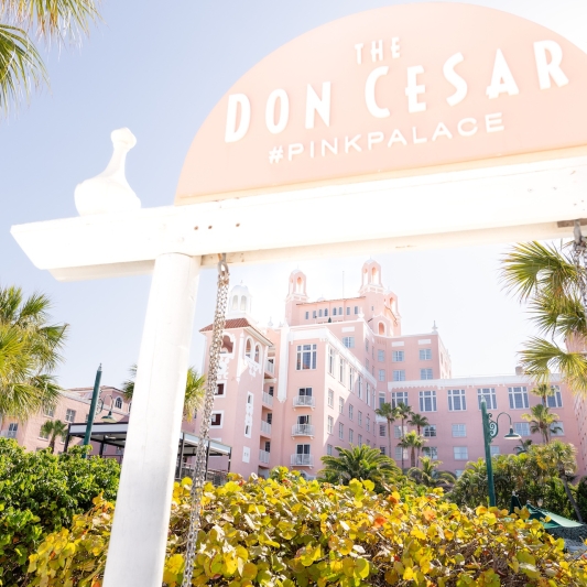 a beach swing with a large pink hotel in the background