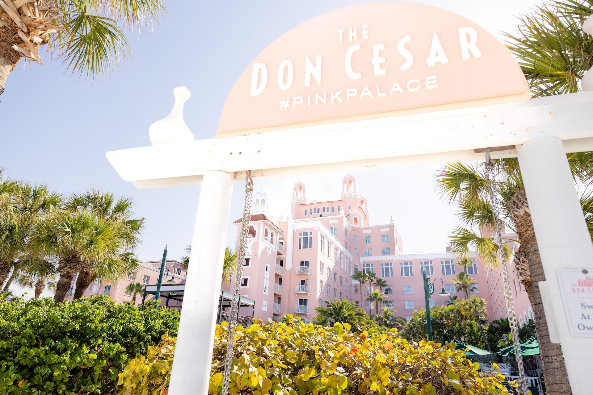 a beach swing with a large pink hotel in the background