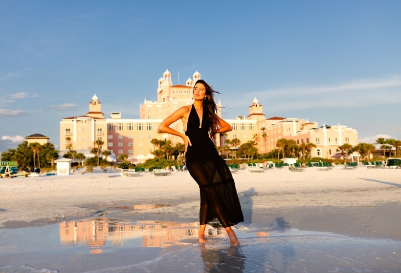 a woman in a black coverup posing on the beach