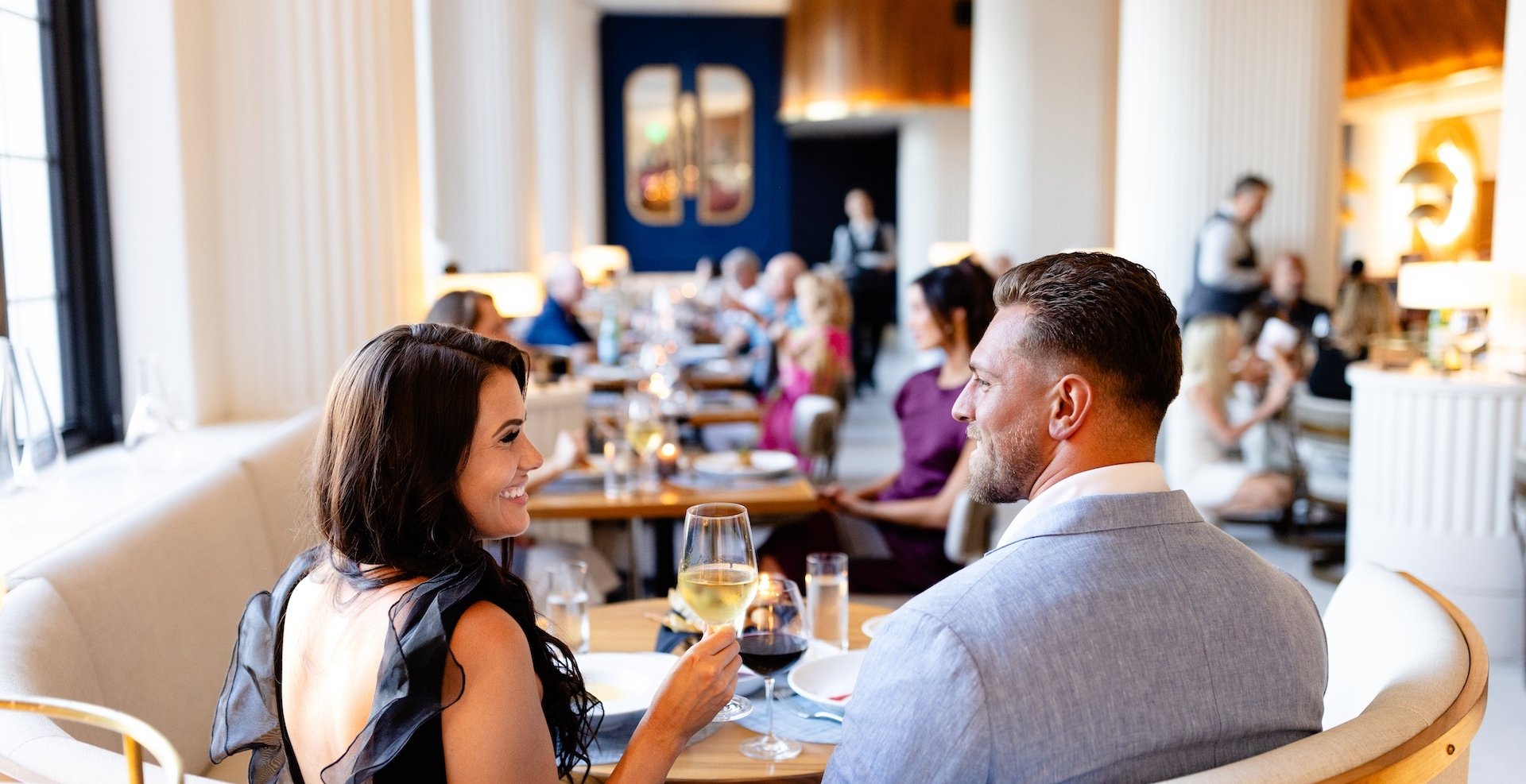 a couple eating dinner and drinking wine in a booth