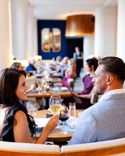 a couple eating dinner and drinking wine in a booth