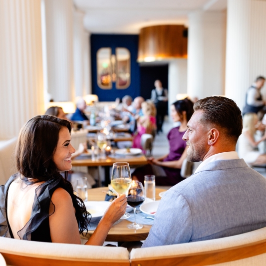 a couple eating dinner and drinking wine in a booth