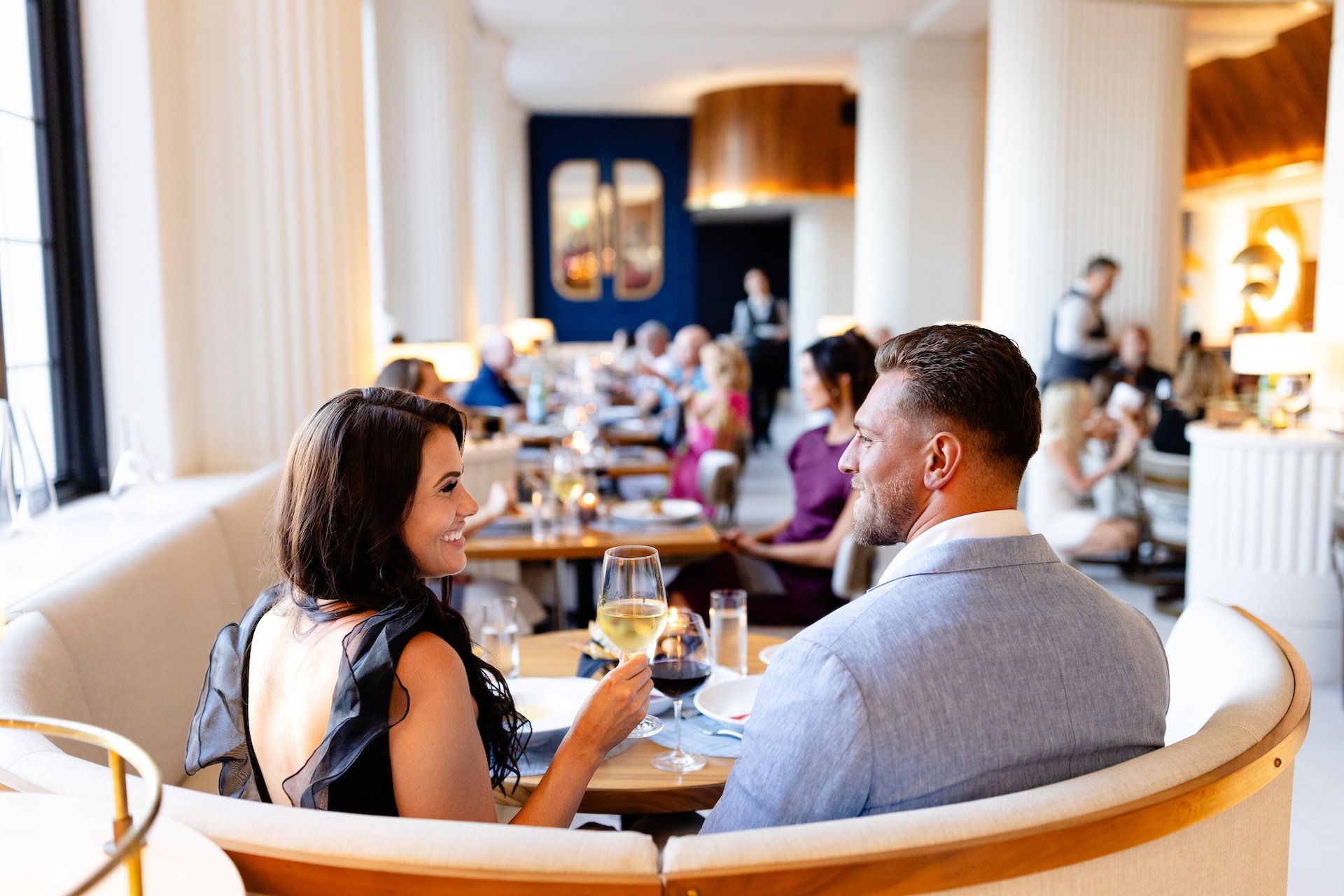 a couple eating dinner and drinking wine in a booth