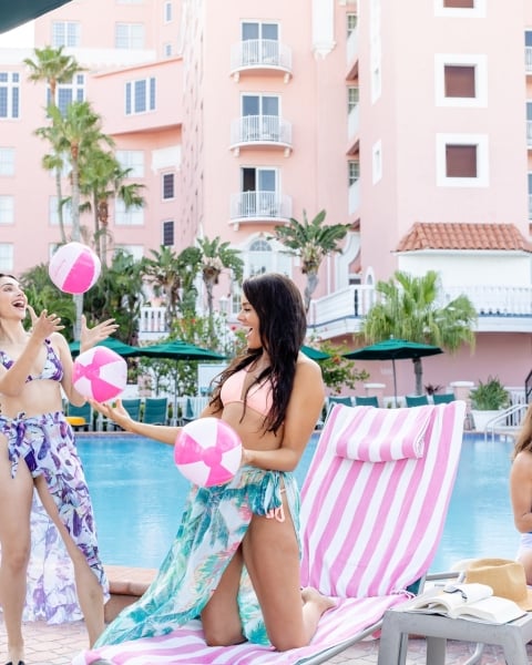 women relaxing by the pool with cocktails and beach balls