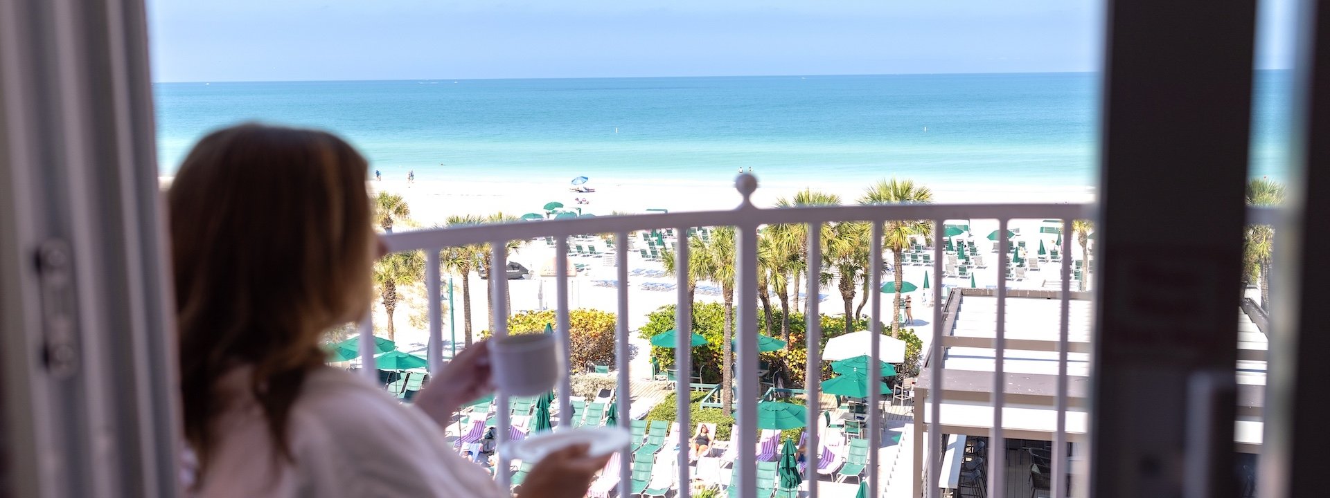 a woman drinking coffee on a balcony