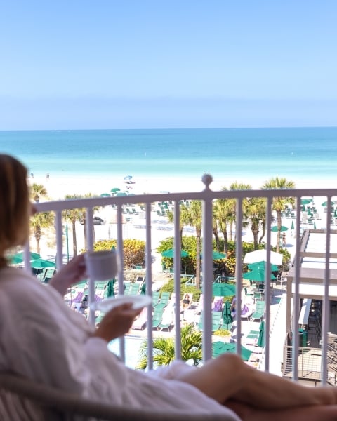 a woman drinking coffee on a balcony